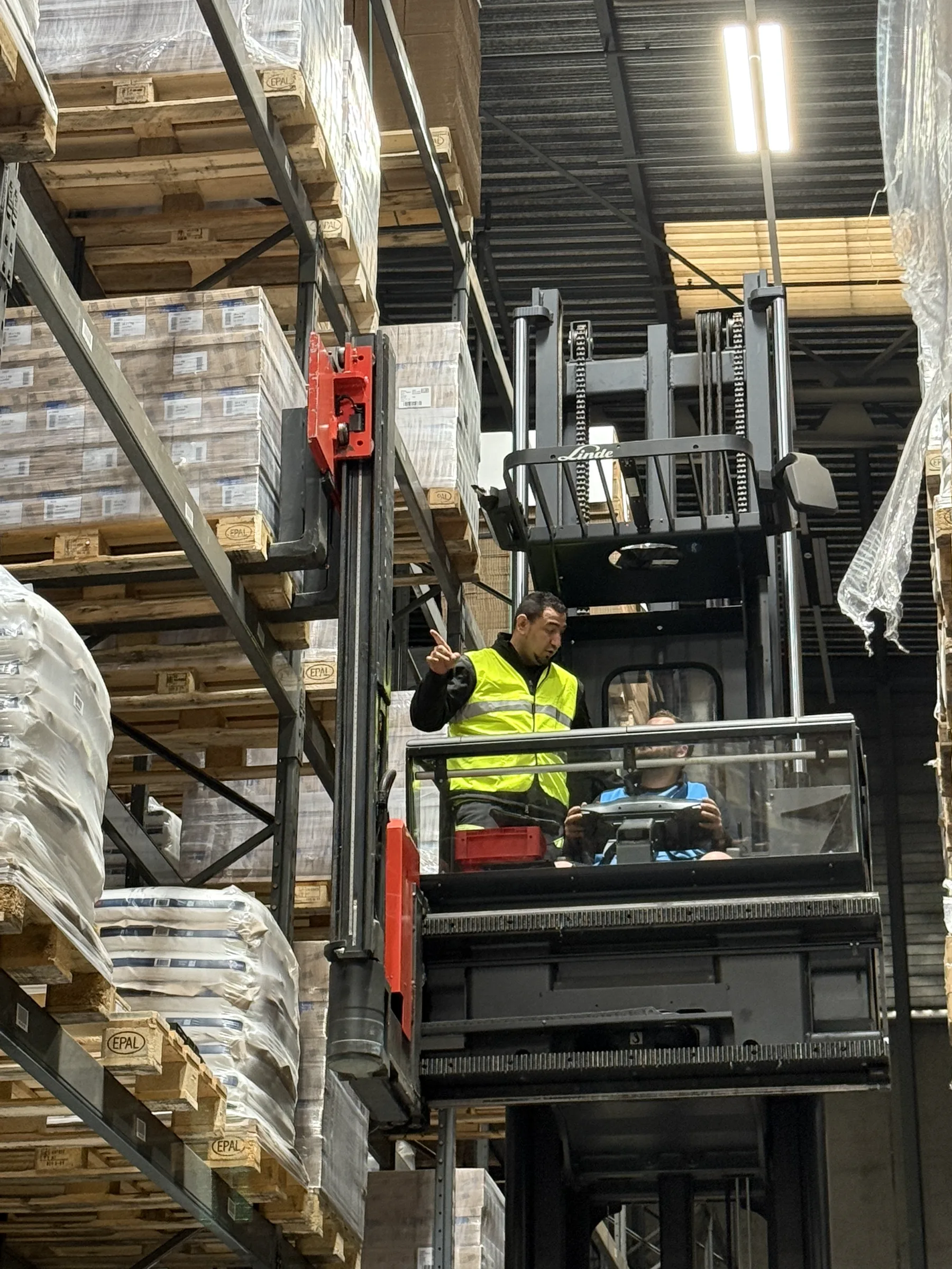 Ausbildner begleitet Teilnehmende im Hochregal